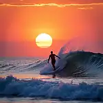 Surfer riding a wave in the ocean at sunset